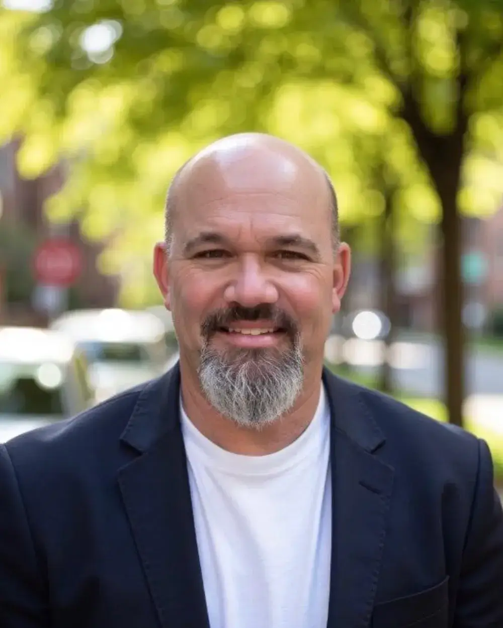Shane Giles, owner of Giles Heating and Air, smiling outdoors on a tree-lined street